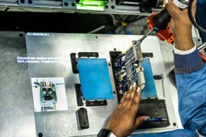 Over-the-should look at manufacturer at L3Harris assembling electronics with LightGuide projected augmented reality work instructions and smart torque tool